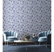 Vardagsrum med blommönstrad tapet, två fåtöljer, ett soffbord och ett sidobord.