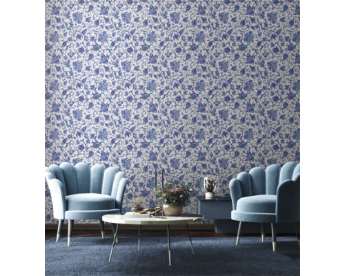 Vardagsrum med blommönstrad tapet, två fåtöljer, ett soffbord och ett sidobord.