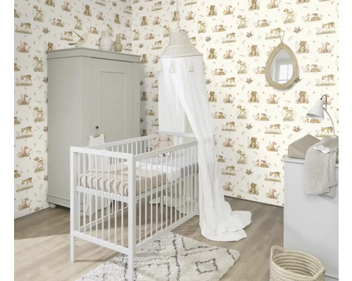 Barnrum med spjälsäng, skötbord och skåp framför en tapet med djurmotiv.