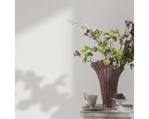 Dekorativ blomvas med blommor, kaffekopp och bakverk på ett sidobord