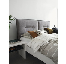 Säng med grå tygklädd sänggavel och vitt sängbord