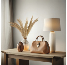 Dekorativ scen med väska, lampa och vaser på ett träbord.