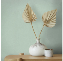 Tapet med textil mönster, vas med fläktblad på ett bord