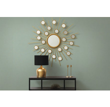 Dekorativ inredning med spegel i form av en sol, lampa och ljusstakar på en hylla.