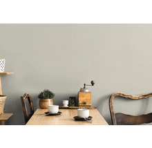 Ett ljust rum med ett träbord, två stolar, koppar och dekorationer på väggen