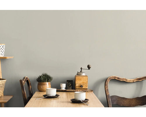 Ett ljust rum med ett träbord, två stolar, koppar och dekorationer på väggen