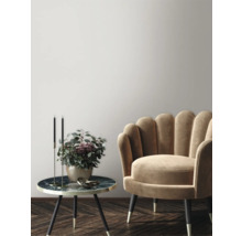 Dekorativ scen med fåtölj, sidobord, ljusstakar och blomvas i en elegant miljö.