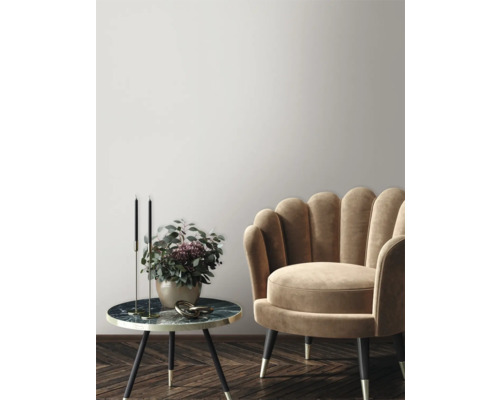 Dekorativ scen med fåtölj, sidobord, ljusstakar och blomvas i en elegant miljö.