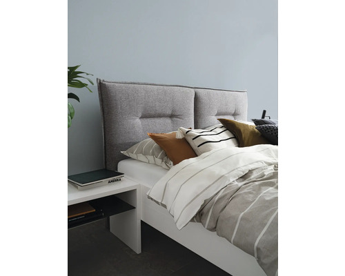 Sovrum med säng, vadderad sänggavel, kuddar och nattduksbord