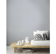 Ljust vardagsrum med soffa, kuddar, bord och porslin