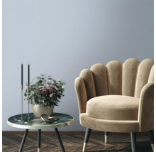 Dekorativt vardagsrum med fåtölj och sidobord med blomsterarrangemang.