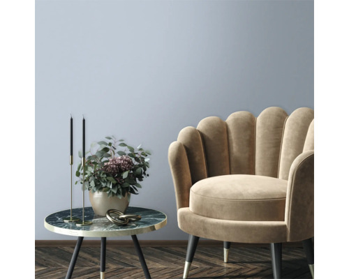 Dekorativt vardagsrum med fåtölj och sidobord med blomsterarrangemang.