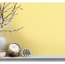 Dekorativ scen med klocka, vas och växtdekoration framför en vägg