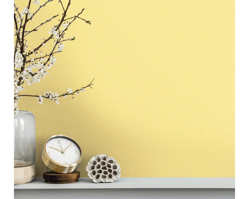 Dekorativ scen med klocka, vas och växtdekoration framför en vägg