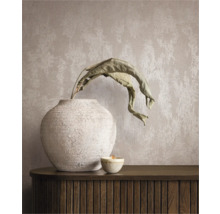 Dekorativt stilleben med vas, växt och ljus på en skänk framför en väggtapet.