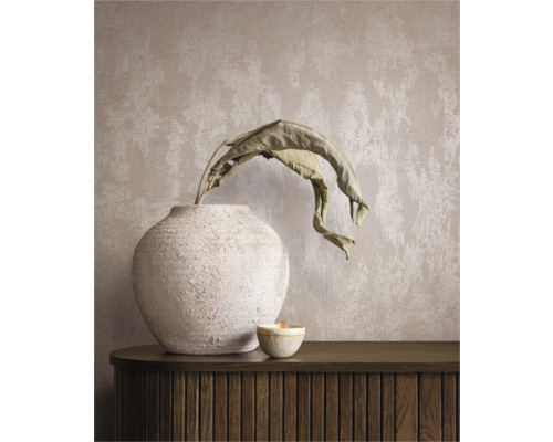 Dekorativt stilleben med vas, växt och ljus på en skänk framför en väggtapet.