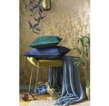 Dekorativt arrangemang med kuddar, pall, filt, växt och dekorativ figur för en mysig atmosfär