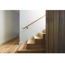 Trappa med trätrappsteg och ledstång mot en vit vägg