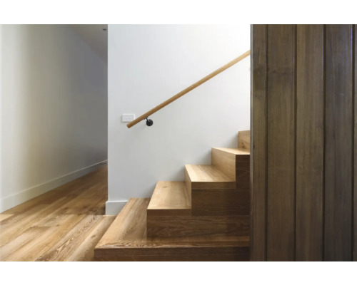 Trappa med trätrappsteg och ledstång mot en vit vägg