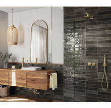 Badrum med tvättställsskåp i trä, spegel, dusch och väggplattor