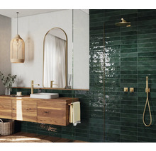 Modernt badrum med tvättställ i trä, spegel, hängande lampa och gröna kakelplattor i duschen