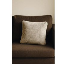 Fyrkantig prydnadskudde med fuskpälslook på en brun soffa