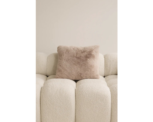 Fyrkantig prydnadskudde med pälsutseende på en soffa.