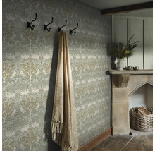 Detaljbild av ett rum med mönstrad tapet, hatthylla, filt och öppen spis