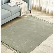 Fyrkantig matta med fransar bredvid en soffa på ett trägolv