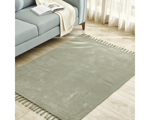 Fyrkantig matta med fransar bredvid en soffa på ett trägolv