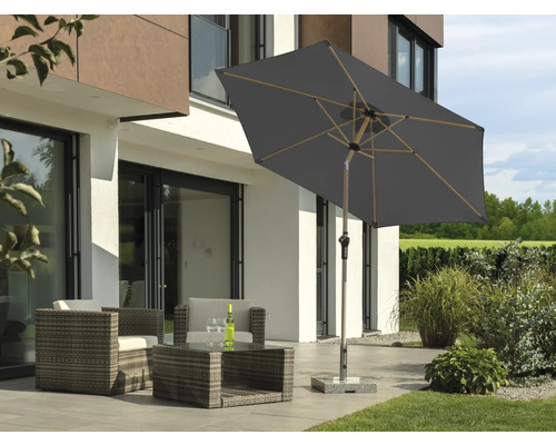 Trädgårdslounge med parasoll på terrass framför modernt hus