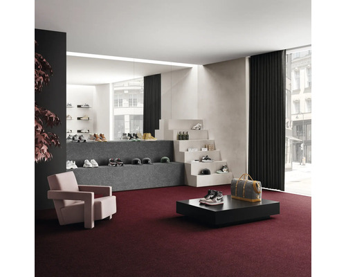 Interiör med heltäckningsmatta, fåtölj, bord och varudisplay av skor och accessoarer