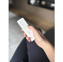 En hand håller en vit fjärrkontroll.