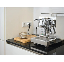 Espressomaskin i rostfritt stål på köksbänk med kopp och skärbräda