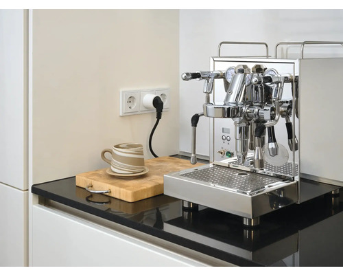 Espressomaskin i rostfritt stål på köksbänk med kopp och skärbräda