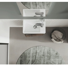 Översikt av ett badrum med handfat, blandare, spegel, rund matta och tvättkorg