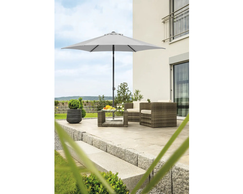 Trädgårdsscen med parasoll, rottingfåtöljer och bord på en terrass