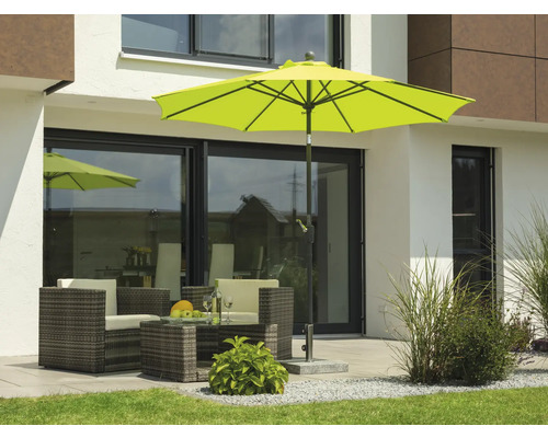 Scen med trädgårdsmöbler under ett parasoll på en terrass framför ett hus.
