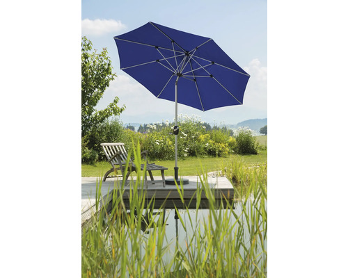 Blått trädgårdsparasoll bredvid en damm och trädäck med solstol