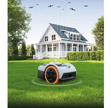 Robotgräsklippare på gräsmatta framför hus med satellitanslutning