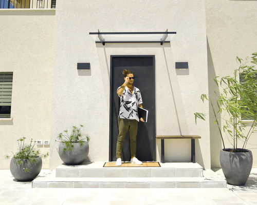 Modern husentré med mörk dörr, entrétak i glas, rektangulära utomhusvägglampor och stora grå blomkrukor på ljusa trappsteg.