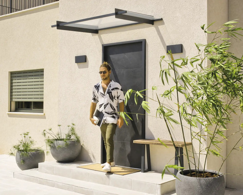 Modern entré med ett svart entrétak, en minimalistisk svart ytterdörr och planteringskärl på en ljus terrass.