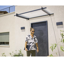 Modernt entrétak med svart metallram och transparent panel över en mörk ingång på en ljus husfasad.