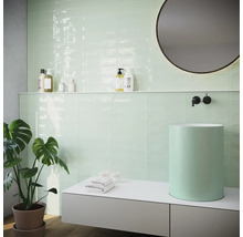 Modernt badrum med mintgröna kakelplattor, tvättställsskål och rund spegel