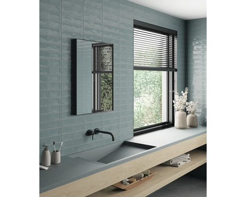 Ljust badrum med handfat, spegel, fönster och kakel