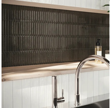 Väggdekoration med avlånga, mörka plattor och armatur