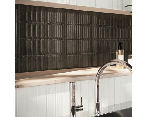 Väggdekoration med avlånga, mörka plattor och armatur