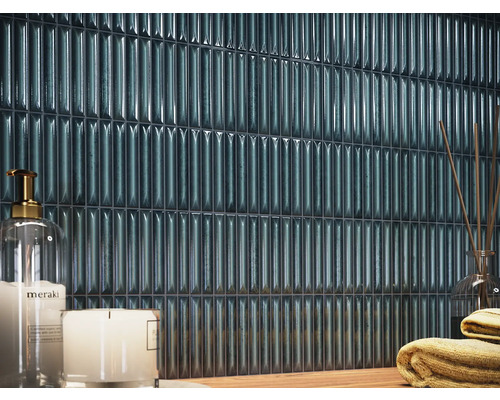 Väggkakel i ett badrum med ljus och handdukar