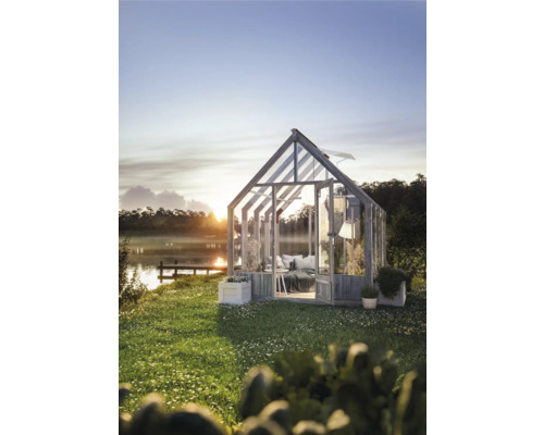 Växthus i trädgården med utsikt över sjön vid soluppgången.