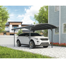 Bil under en carport på en stenlagd uppfart framför ett hus